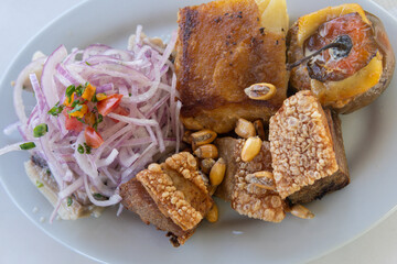 A typical Peruvian country dish from Arequipa called Triple with ceviche, crispy pork, and stuffed rocoto peppers. Closed shot.