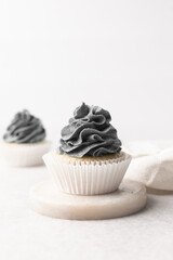 grey frosting on cupcakes with a white background, cupcakes in white liners with tall buttercream swirl, grey buttercream frosted cupcakes on a white background