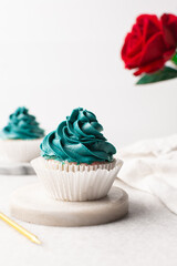 blue frosting on cupcakes with a white background, cupcakes in white liners with tall buttercream swirl, blue buttercream frosted cupcakes on a white background