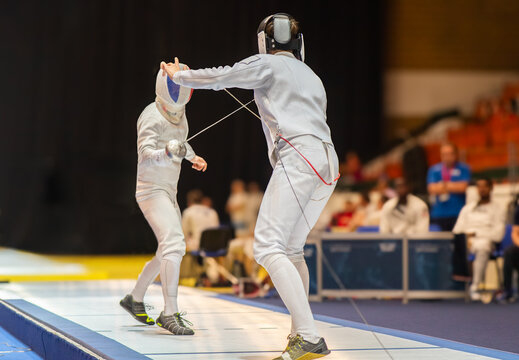  Two fencing athletes fight on professional sports arena