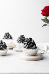 grey frosting on cupcakes with a white background, cupcakes in white liners with tall buttercream swirl, grey buttercream frosted cupcakes on a white background