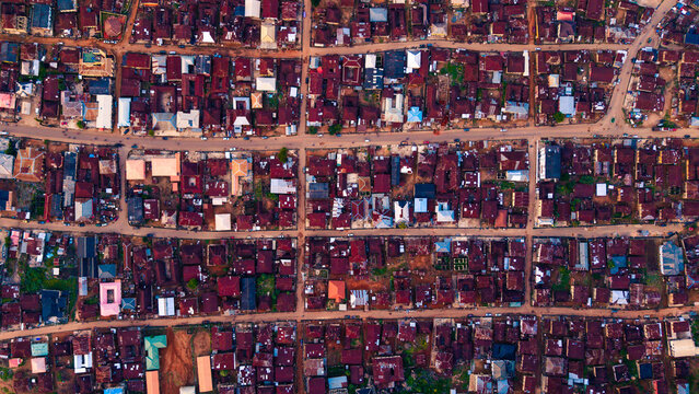 Aerial view of closely packed red-roofed houses intersected by straight roads create a striking grid pattern against the earth tones of the landscape, Idanre, Ondo, Nigeria.