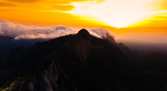 Aerial view of rocky outcrops rise majestically against a fiery sunset, their peaks kissing the clouds in a dance of light and shadow, Idanre, Ondo, Nigeria.