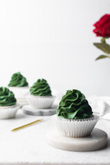 green frosting on cupcakes with a white background, cupcakes in white liners with tall buttercream swirl, green buttercream frosted cupcakes on a white background