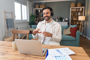Young freelancer leading an online video meeting from a cozy home office smiling man with...