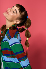 Young womans stylish pose against a vibrant pink backdrop showcasing modern fashion trends