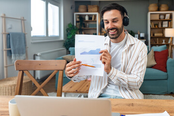 Young freelancer leading an online video meeting from a cozy home office smiling man with...