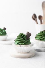 green frosting on cupcakes with a white background, cupcakes in white liners with tall buttercream swirl, green buttercream frosted cupcakes on a white background