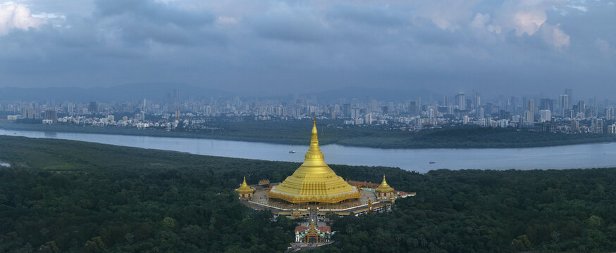 Aerial view of the golden Global Vipassana Pagoda gleaming against the backdrop of the cityscape and calm waters, Mumbai, Maharashtra, India.