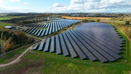 Aerial view of rows of solar panels reflecting the sky's blue hues amidst fields of green and gold, creating a tapestry of sustainable energy, Mansfield, England, United Kingdom.