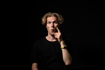 Surprised man in black shirt with wide eyes and shocked expression under dramatic light