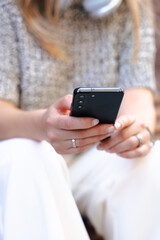Close up of woman hands holding smartphone outdoors in modern urban environment, concept of technology, communication, digital lifestyle, connection, online social media, texting, internet browsing.