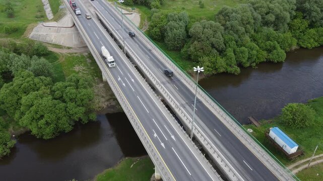 Cars and trucks drive along the road bridge across the Protva river on the federal highway M-3 "Ukraina", aerial view: Kaluga region, Russia - May 26, 2021