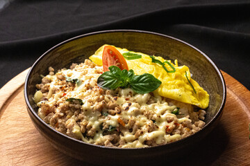 45 Degree View of Ground Chicken Mozzarella Rice Bowl with Torched Mozzarella Cheese and Egg on Top of Circle Wooden Table and Black Background