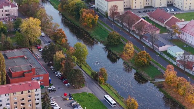 The Morava River flowing through the city of Olomouc, with a rower paddling down it. A drone view of autumn in the Czech Republic.