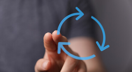 Hand touching a circular arrow symbol, representing concepts like recycling, renewal, or software refresh. Illustrative of cycles and processes.