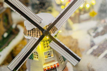 close up of a miniature windmill house with snow covered blades and roof in a christmas village display concept of seasonal tradition, holiday decor