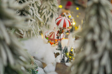 miniature santa claus figure descending via a red and white parachute over a snowy christmas village display concept of holiday storytelling, seasonal retail, festive advertisement.
