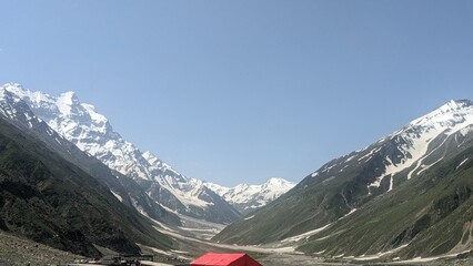 Vast mountain valley with snow-capped peaks under a clear blue sky, showcasing natural beauty and remote wilderness.