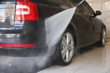 Washing auto with high pressure water jet at car wash, closeup