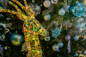 glowing gold wire reindeer head ornament on a christmas tree decorated with blue and silver baubles concept of festive decoration, winter retail, holiday greeting