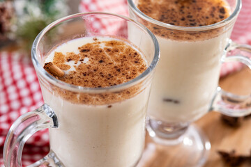 Eggnog with Cinnamon and Christmas Decorations on wooden table