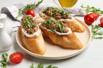 Delicious bruschettas with tuna, tomatoes and arugula on white table, closeup