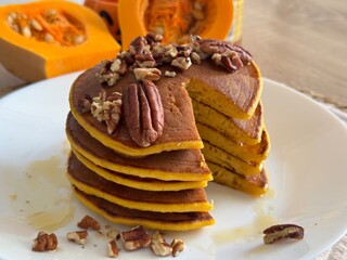 chocolate cake with nuts and raisins  Close-up of fluffy pumpkin pancakes with creamy chocolate topping and chopped pecans. Fresh pumpkins blurred in the background. Perfect autumn dessert.
