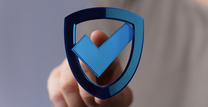 A hand interacts with a digital shield icon featuring a check mark. This photo symbolizes security, protection, and verification in d