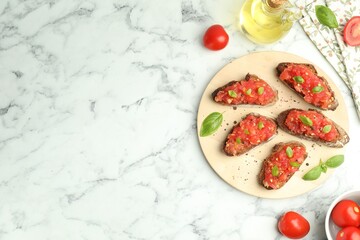 Tasty bruschettas with tomatoes, basil and oil on white marble table, flat lay. Space for text