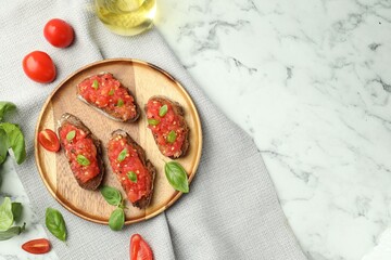 Tasty bruschettas with tomatoes and basil on white marble table, flat lay. Space for text