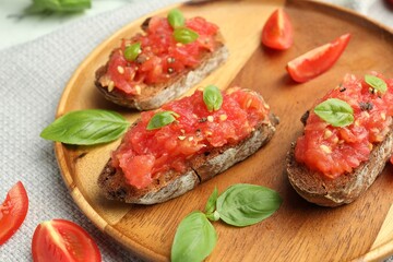 Tasty bruschettas with tomatoes and basil on table, closeup