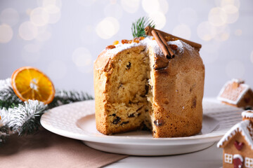 Christmas food. Delicious Panettone cake and festive decor on white wooden table against background with blurred lights, closeup