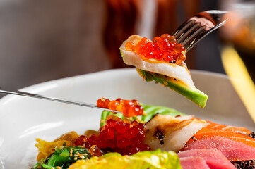 A delicious and vibrant close-up of a fresh sushi dish with raw fish, avocado, and glistening red...