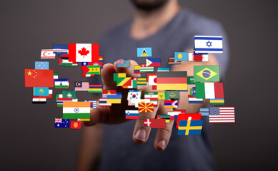 A person's hand touching various flags symbolizing global unity, international relations, and...