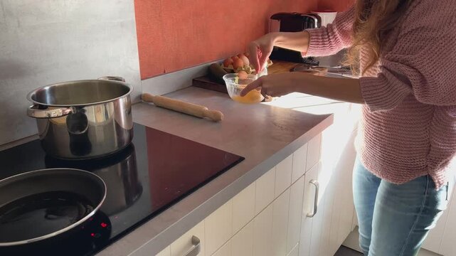 Mujer batiendo un huevo y ech&aacute;ndolo a la sart&eacute;n, cocina casera
