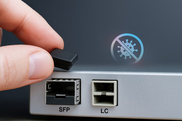 Hand removing protective cap from fiber optic port on network device with technology preventing virus contamination
