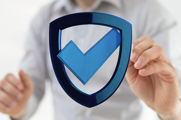 A person's hand holding a blue shield with a checkmark, representing security, validation, and protection. Ideal for business, techno