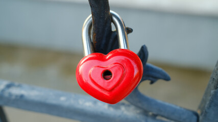 Red heart love lock attached to outdoor metal railing