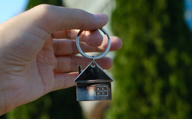 Hand holding house keychain representing home ownership and real estate