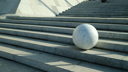 Marble sphere placed on concrete stairs with dramatic shadows