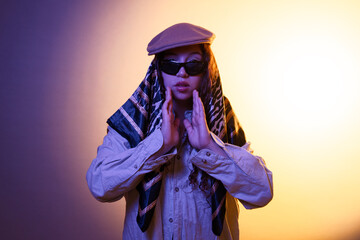 Stylish woman wearing beret and sunglasses posing in studio
