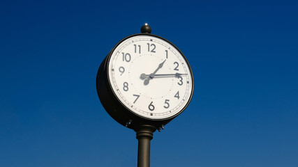 Vintage outdoor clock against clear blue sky