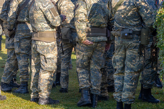 A group of soldiers from the back, parts of military uniforms and pouches.