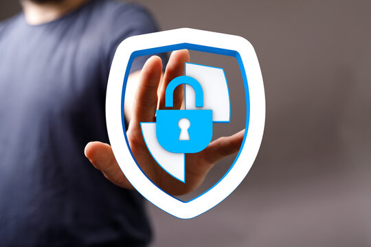 A person's hand protects a shield with padlock icon representing security, safety, and online protection. Concept of secure data, cyb