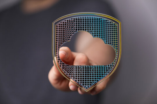Abstract image representing cloud protection and data security, person holding a shield shaped cloud symbol, data storage protection