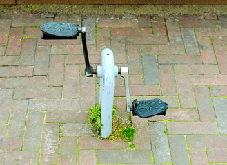 two bicycle pedals mounted on a metal holder which is recessed into the street