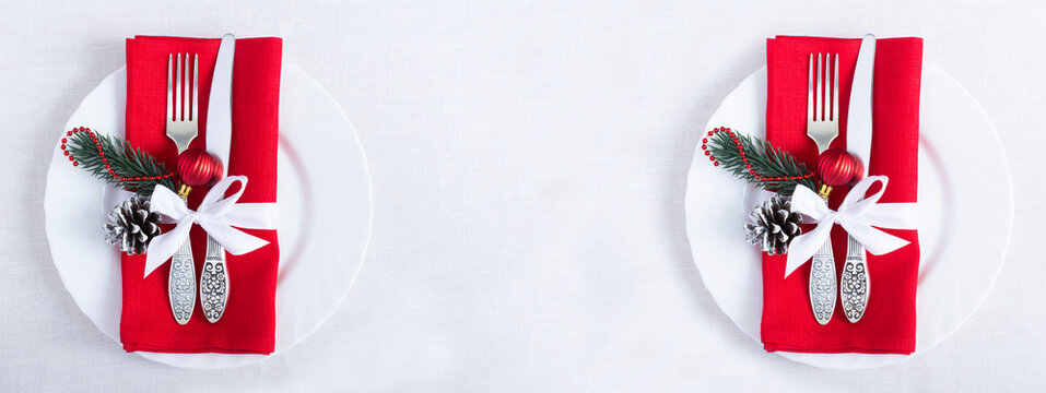 Christmas setting the table with red napkin on the white plate on a white tablecloth. Top view. Copy space.