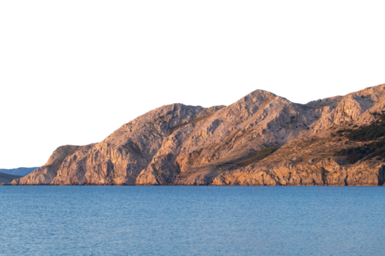 Rugged rocky coastal cliffs at sunset with serene blue sea. Isolated object