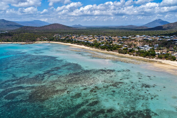 A breathtaking aerial view of Hydeaway Bay on Queensland’s Whitsunday Coast. The turquoise waters, white sandy beaches, and lush tropical landscape create a serene coastal paradise.